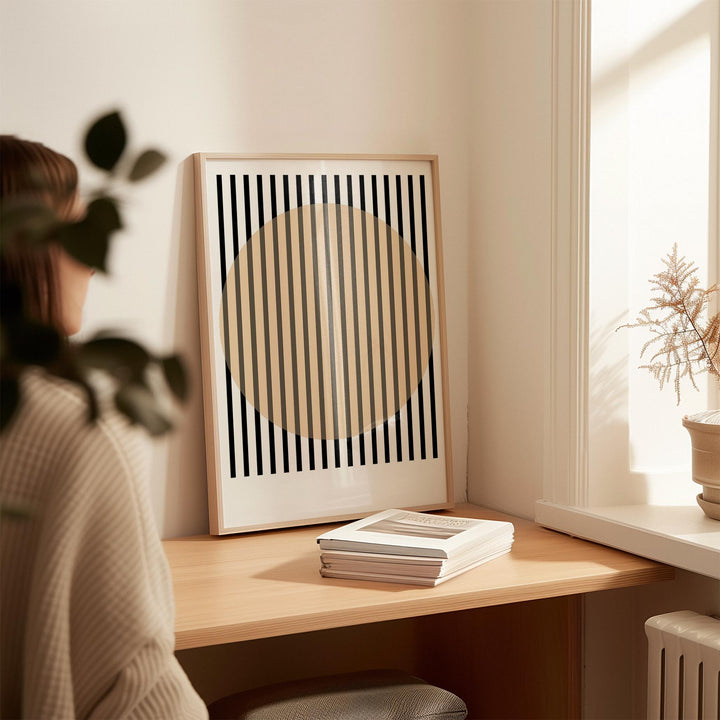 Framed Office Posters art with beige circle and black stripes leaning on a desk with books