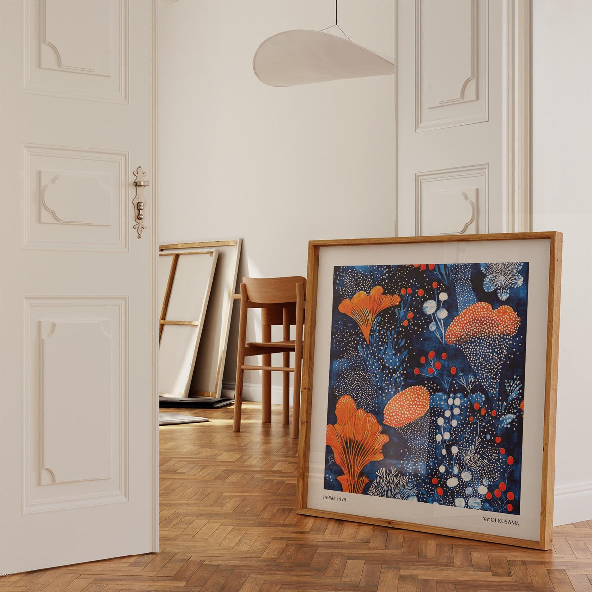 Print leaning on a wooden floor of blue orange wall art with abstract orange floral pattern and white dots