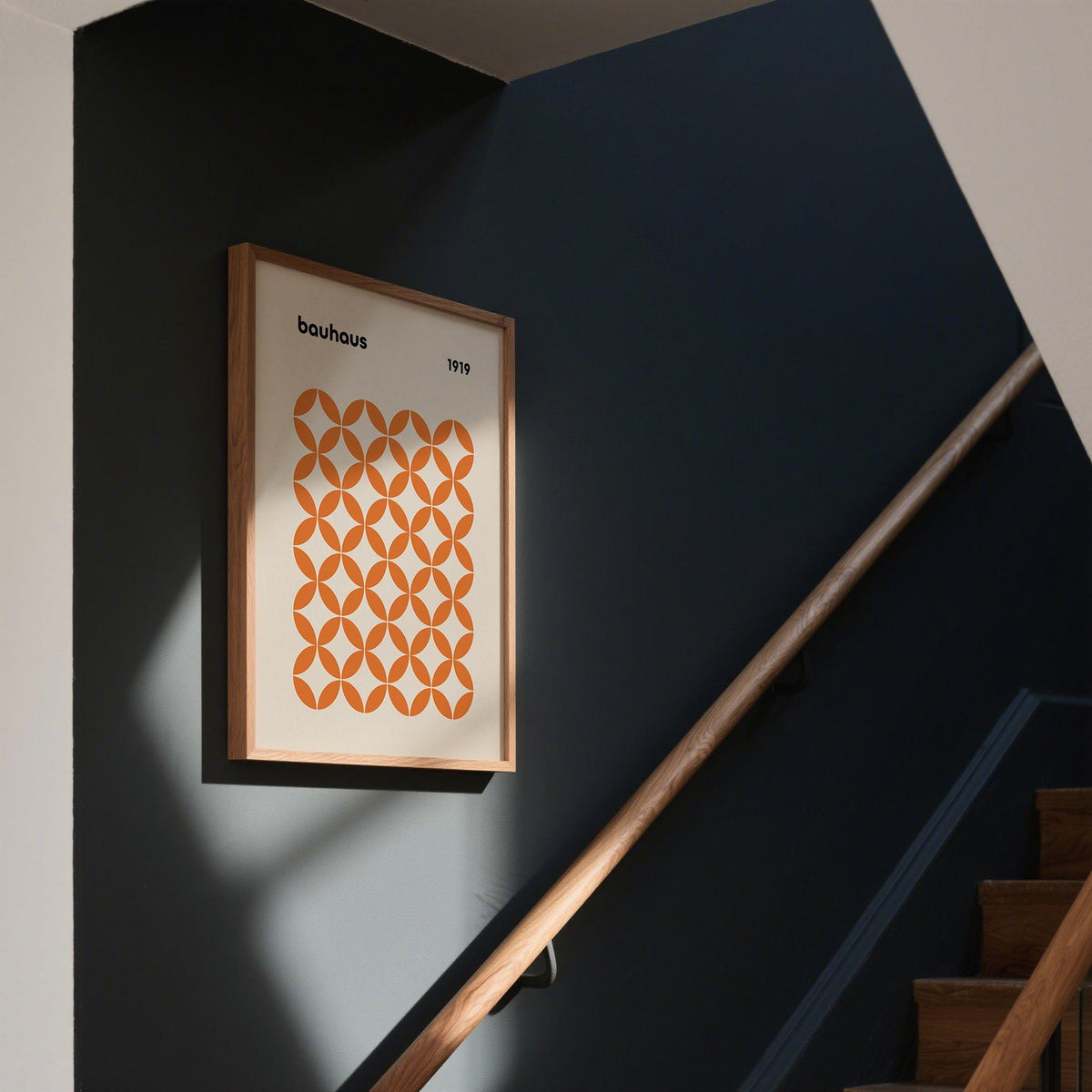 Orange minimalist print with bauhaus style circles on a dark wall by a wooden staircase