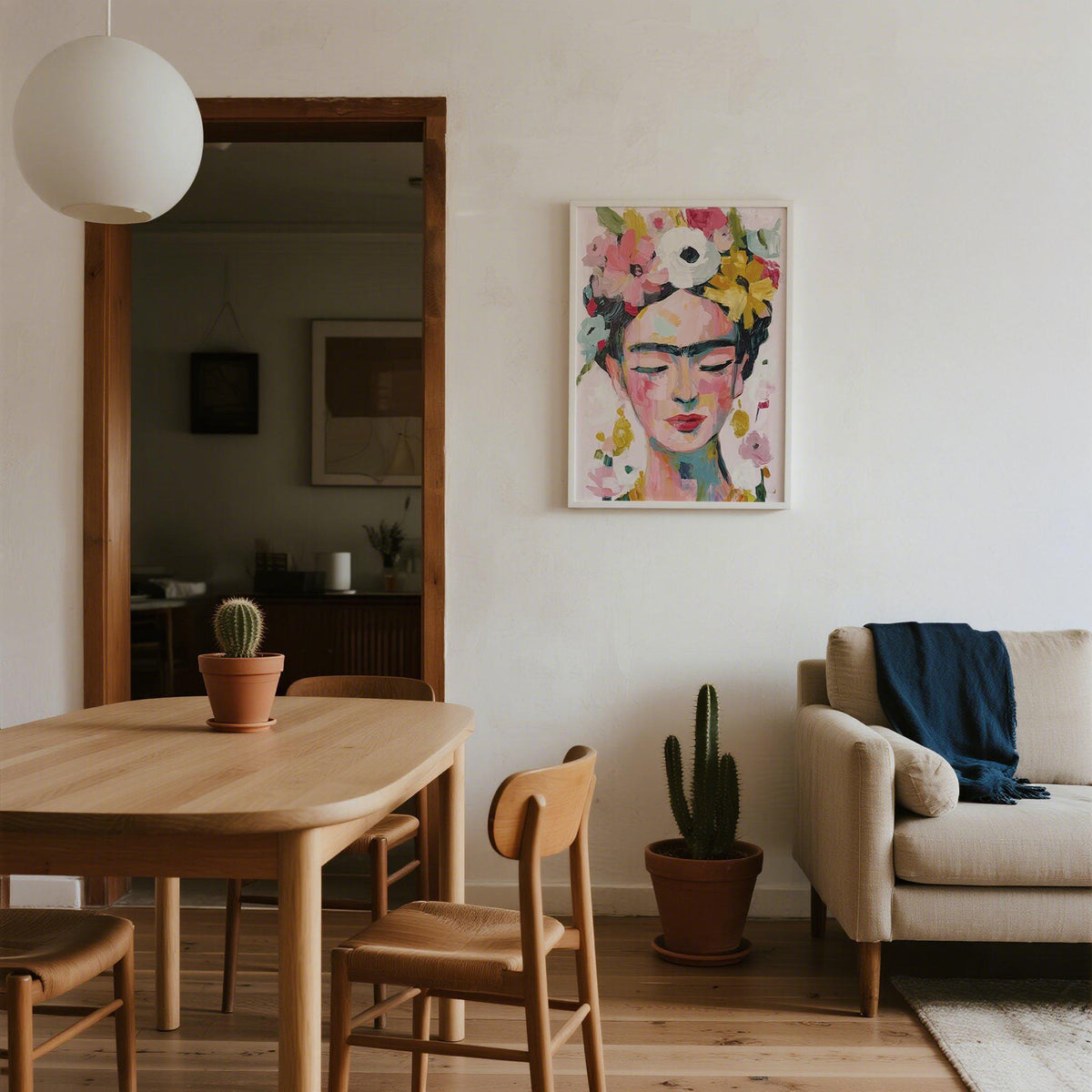 Frida Kahlo paintings hung above a cactus plant in a dining and living room