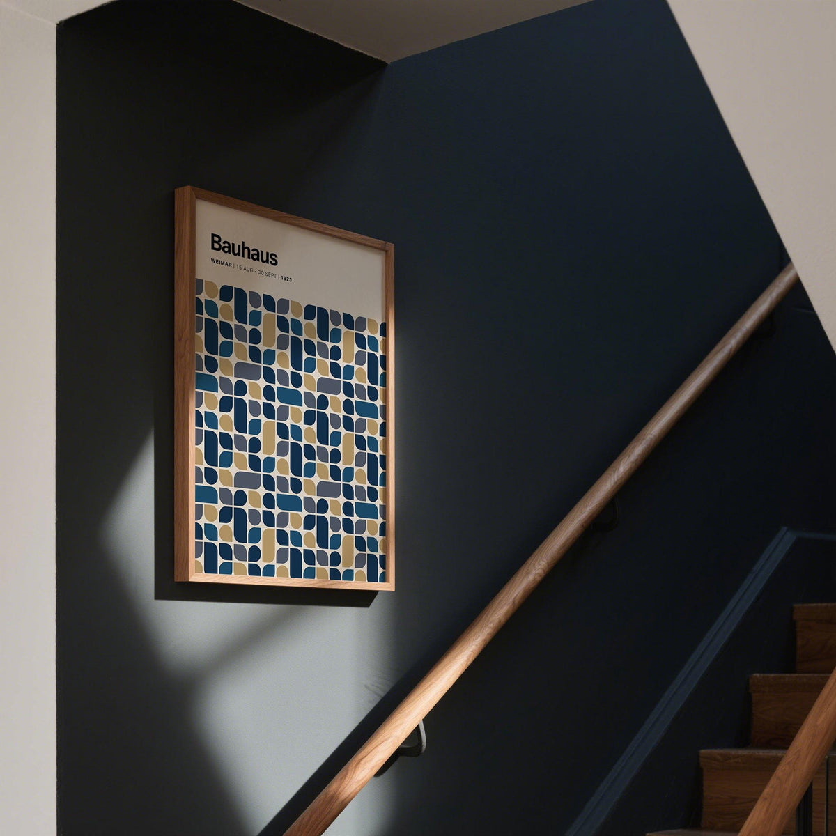 Navy and Gold wall art of a geometric grid pattern in a dark stairway with wooden handrail