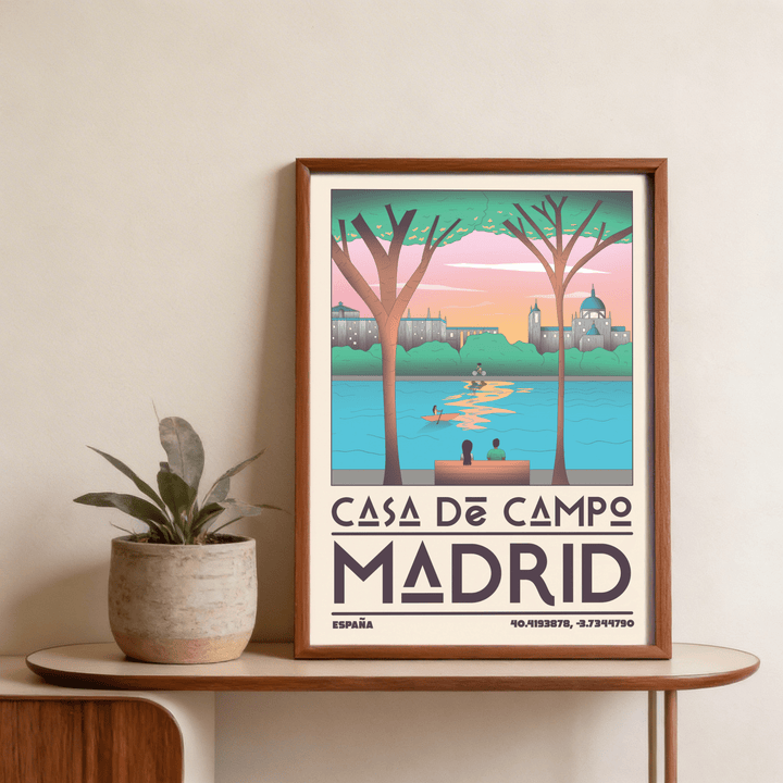 Framed Madrid wall art with a lake view and people sat on a bench beside a potted plant on a shelf