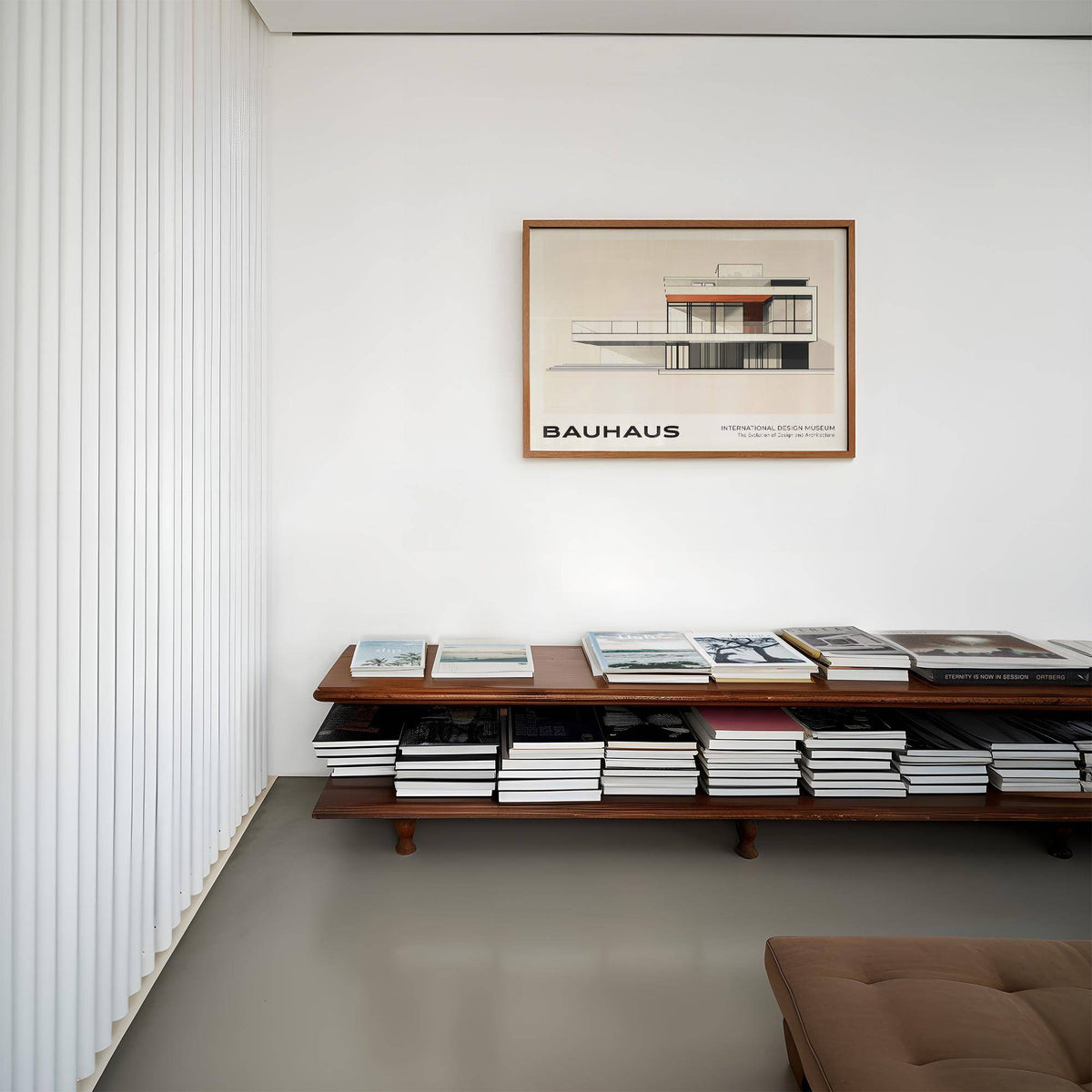 Architecture art print of a modernist building in minimalist bauhaus style above a wooden bookshelf in a white room