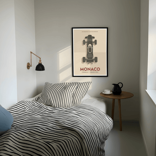 Top-Down Racing Car Poster print on bedroom wall above a striped bedspread and near a small round table