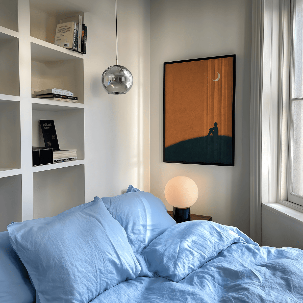 Night Silhouette Poster framed print on a bedroom wall above a table lamp with blue bedding visible