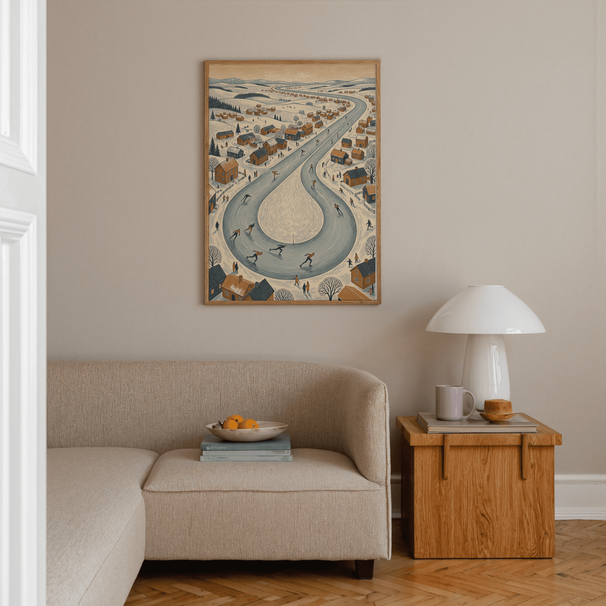 Winter Village Scene print on a wall above a beige sofa with a wooden side table and white lamp