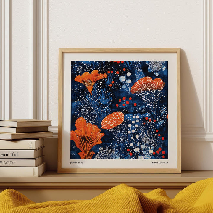 Framed Blue Orange wall art with an abstract orange floral pattern on a dark blue background leaning on a shelf