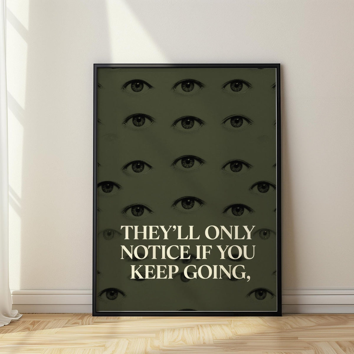 Framed Gym Artwork with human eyes and motivational quote in black and cream leaning on wooden floor