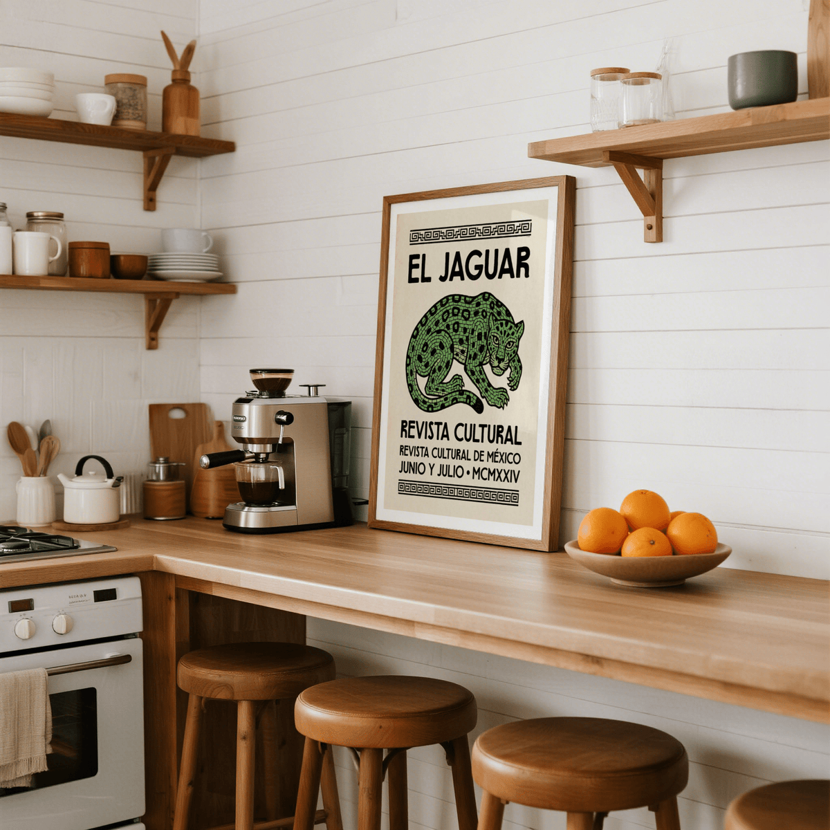 El Jaguar Poster leaning on a wooden kitchen counter with a bowl of oranges and a coffee machine