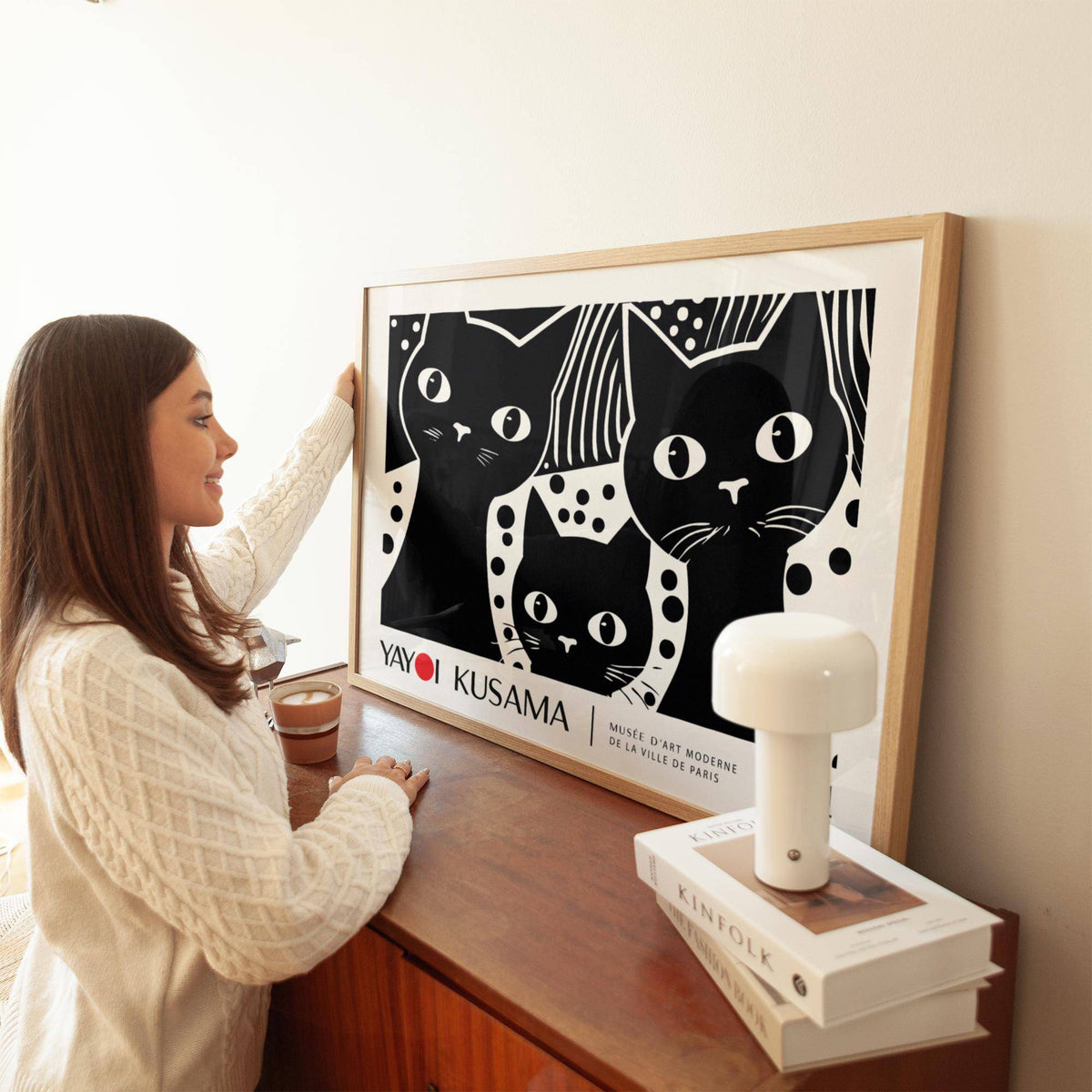 Black Cat wall art in minimalist black and white leaning on a wooden dresser with a lamp