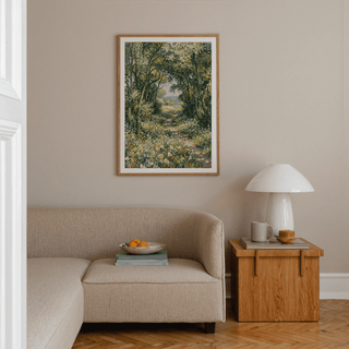 Impressionist art print of a woodland path in green and yellow tones above a beige sofa with a wooden side table