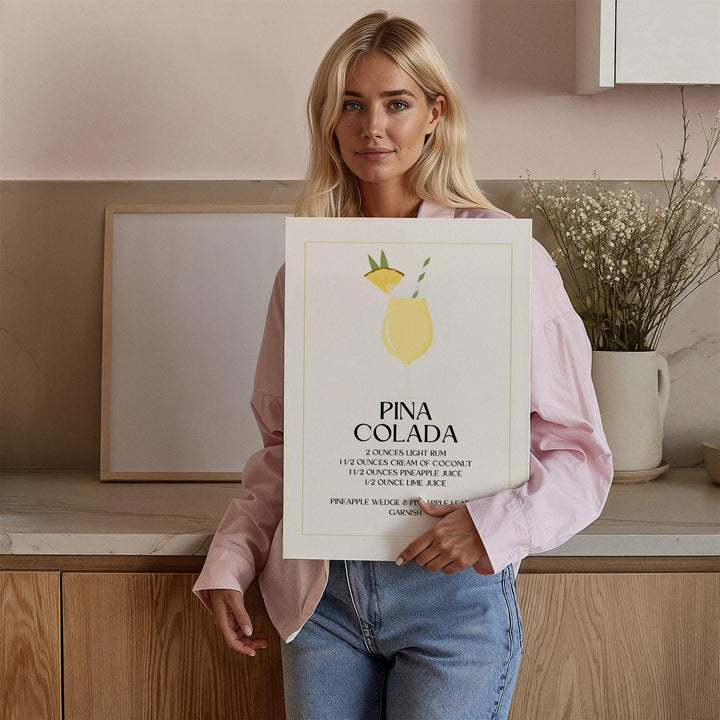 Framed Colada Cream print held by a woman in a kitchen with flowers in a vase