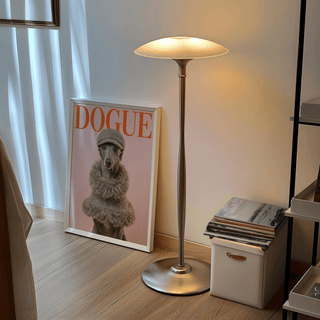 Print leaning on the floor of a greyhound in tweed hat and collar beside a silver lamp