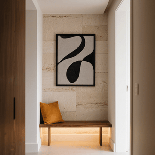 Abstract Black and White Art framed print of an abstract black shape on a white background hung above a wooden bench with an orange cushion