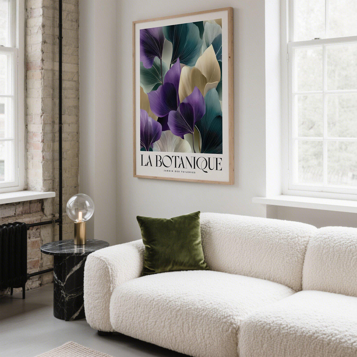Framed print of abstract botanical leaves in purple, cream and green above a cream sofa with a green cushion