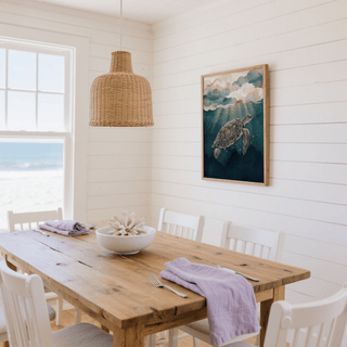Ocean print decor of a watercolour sea turtle with golden accents in a white dining room with wooden table