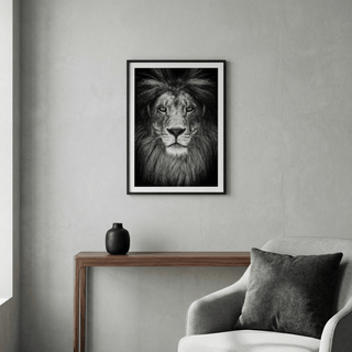 Black and white lion print framed in black above a wooden console with a black vase in a grey room