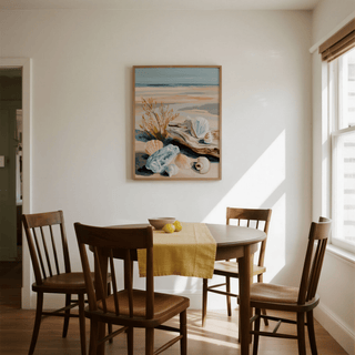 Coastal Shell Art hanging above a round wooden dining table with a yellow runner in a sunlit room