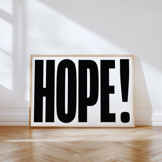 Motivational Work Posters leaning print with bold black hope typography in natural wood frame on wooden floor