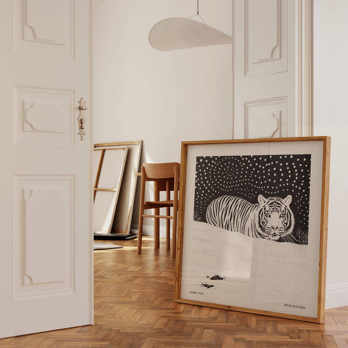 Print leaning on floor with white tiger illustration in natural wood frame near a wood chair