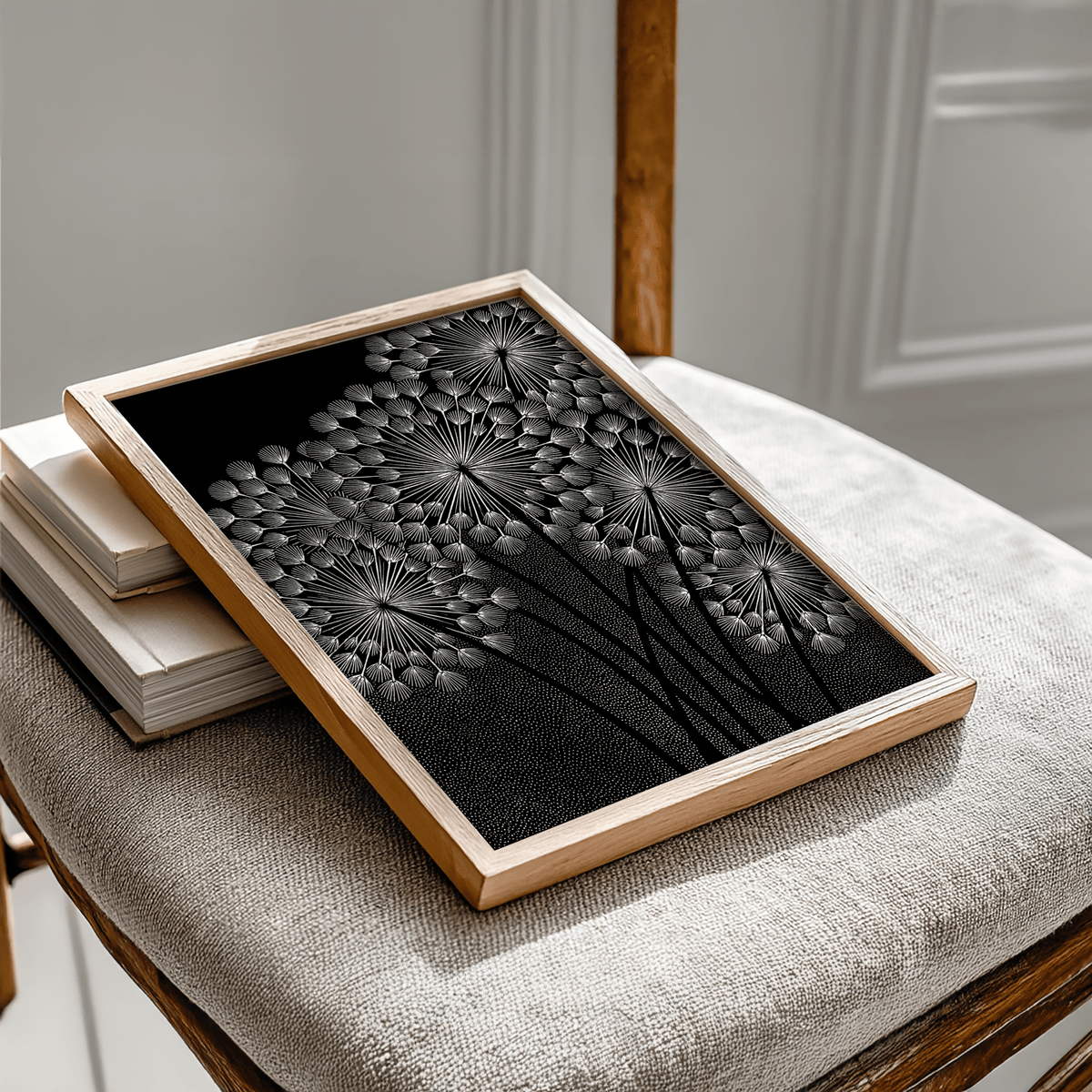 Framed dandelions wall art on a beige chair with a wooden backrest and books