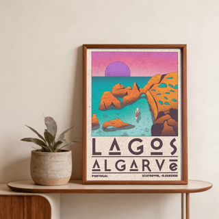 Framed Lagos Algarve wall art of a rocky coastal cove in retro illustration style with purple and orange hues on a table with a plant pot