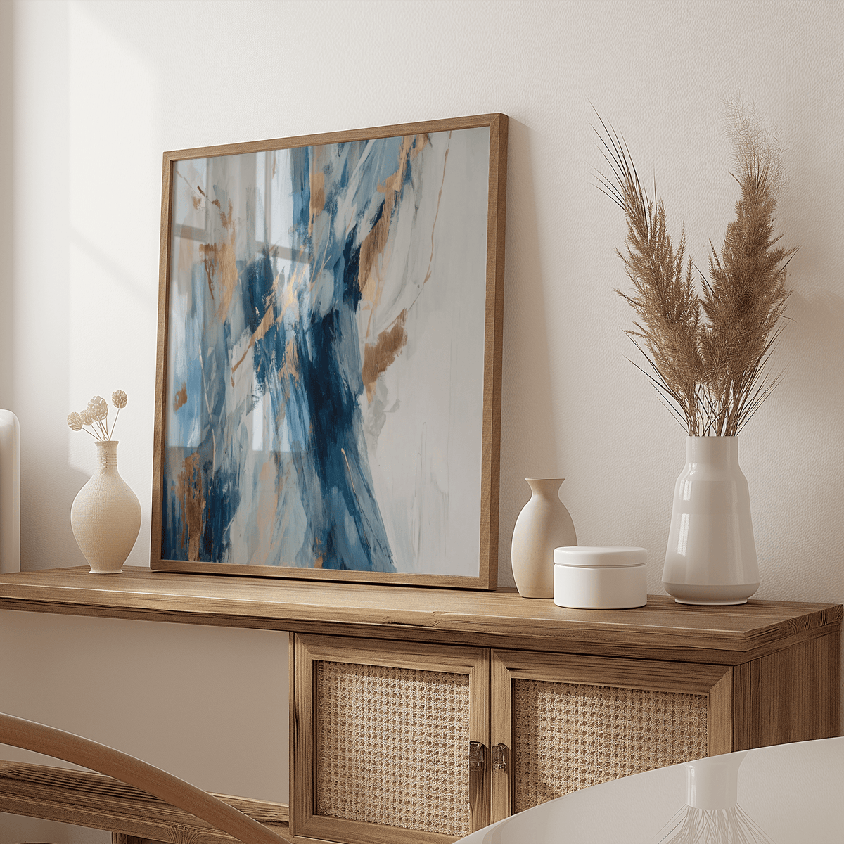 Abstract Blue Wall Art leaning on a wooden sideboard with blue and gold brushstrokes and neutral decor