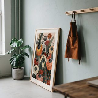 Burnt Orange wall art leaning on a wall with a green monstera plant and orange apron nearby