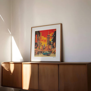 Framed Japonise Art Tokyo Street Dreams print with a retro red and yellow city scene on a wooden sideboard