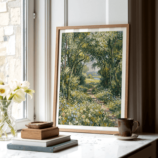 Print leaning on a windowsill of a countryside path with woodland and blue flowers with a brown cup nearby