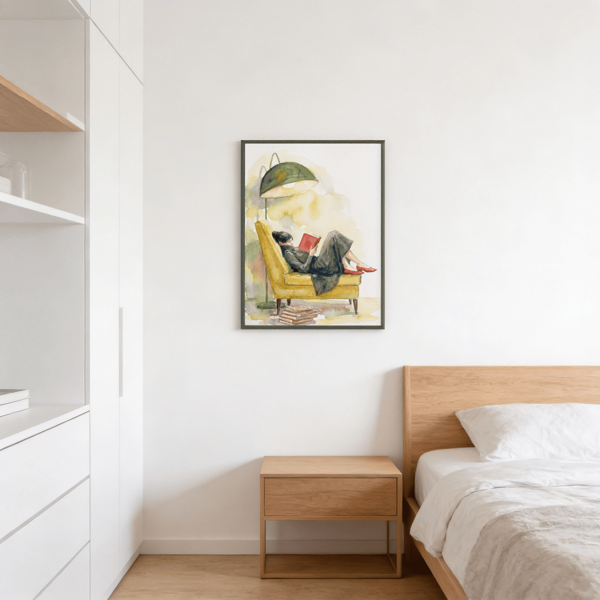 Woman Reading In Armchair print hanging above a bedside table in a bedroom with white walls