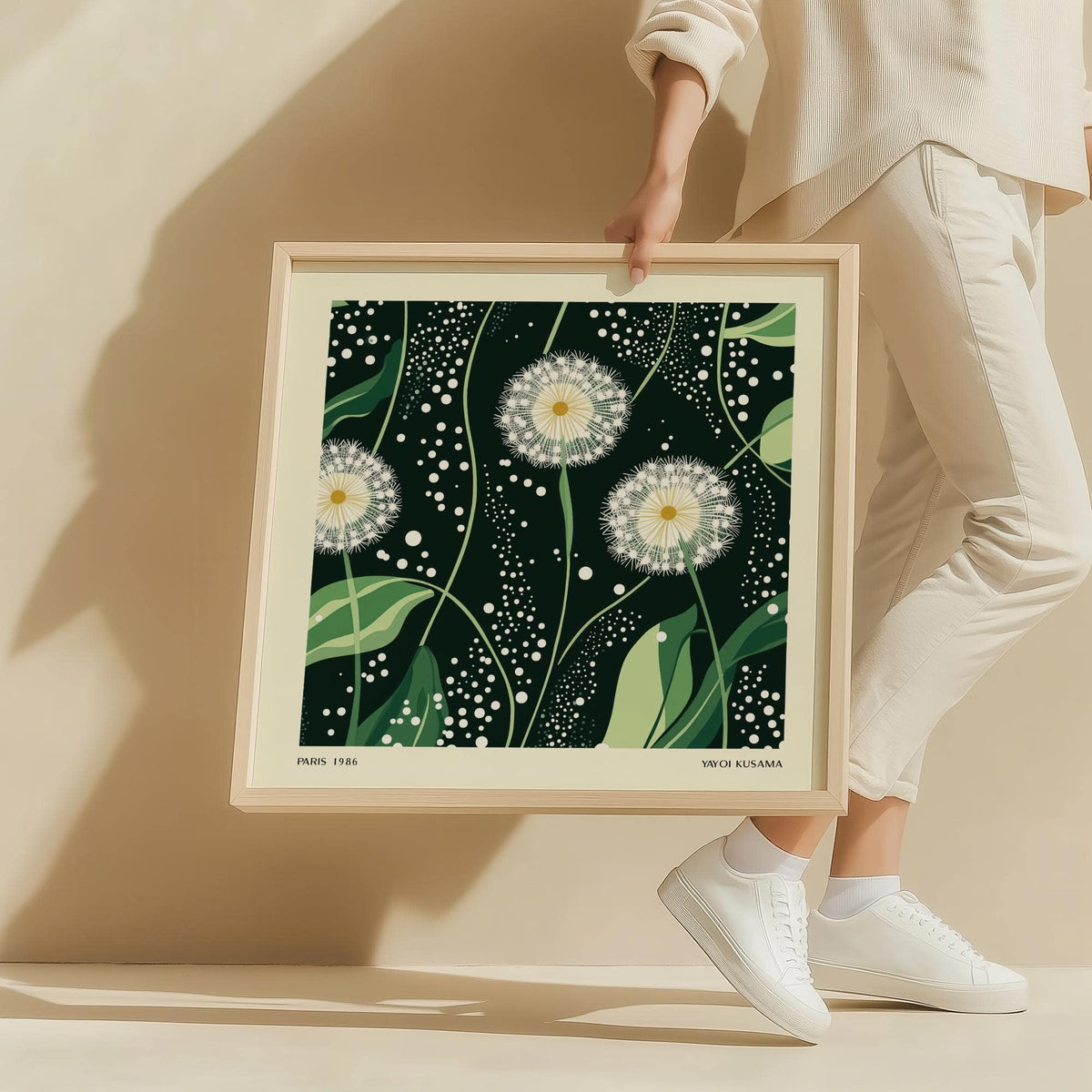 Green wall decor framed print of dandelion seed heads with dark green background held by a person