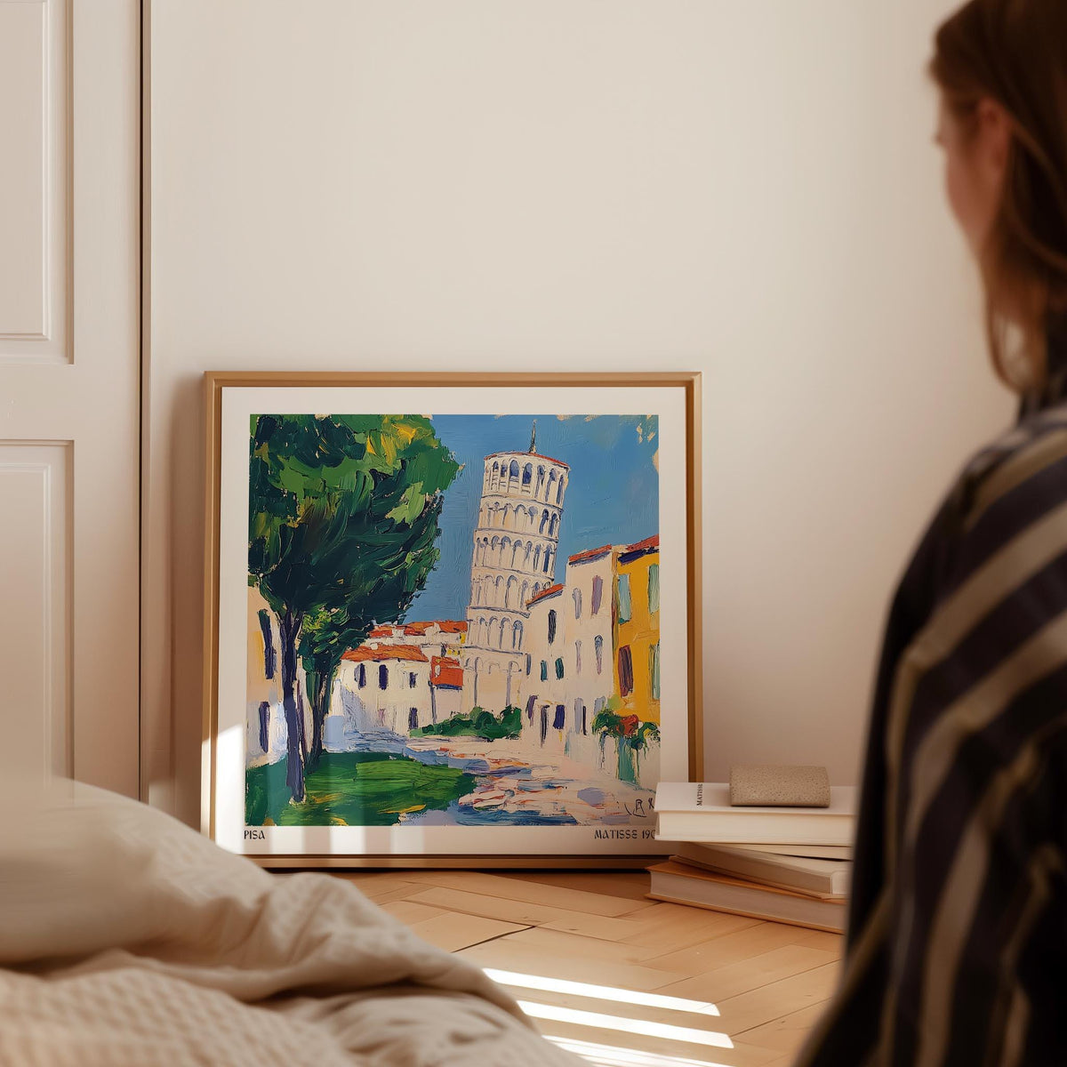 Print leaning on a floor showing the Leaning Tower of Pisa illustration with green trees and blue sky in a cream room