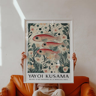 Framed fish artwork print of three red spotted fish with botanical details held above an orange leather armchair