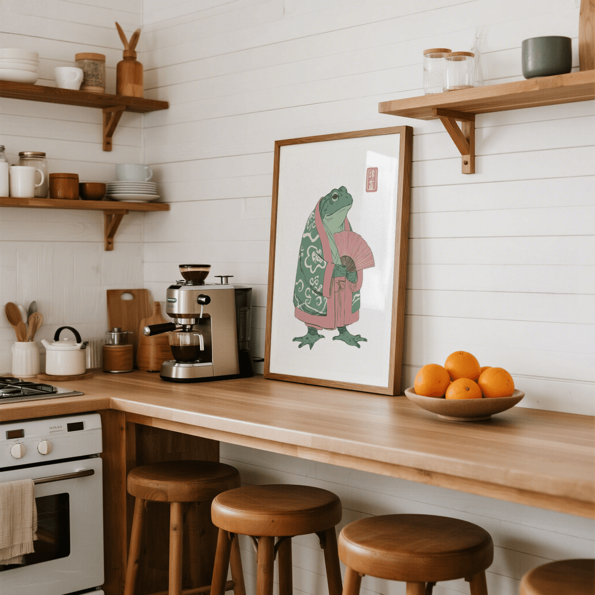 Frog Art Print leaning on a wooden kitchen counter with oranges in a bowl nearby