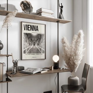 Vienna Architecture Art Print hanging above a wooden desk with a lamp and a chair in a bright room