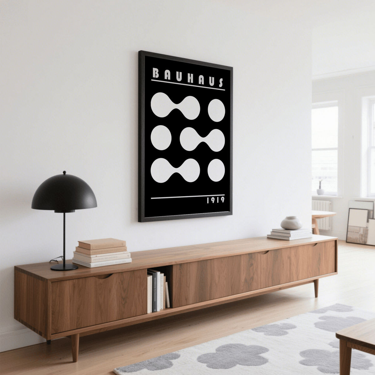 Abstract Geometric Print wall art with white shapes on black background above a sideboard with a lamp in a living room