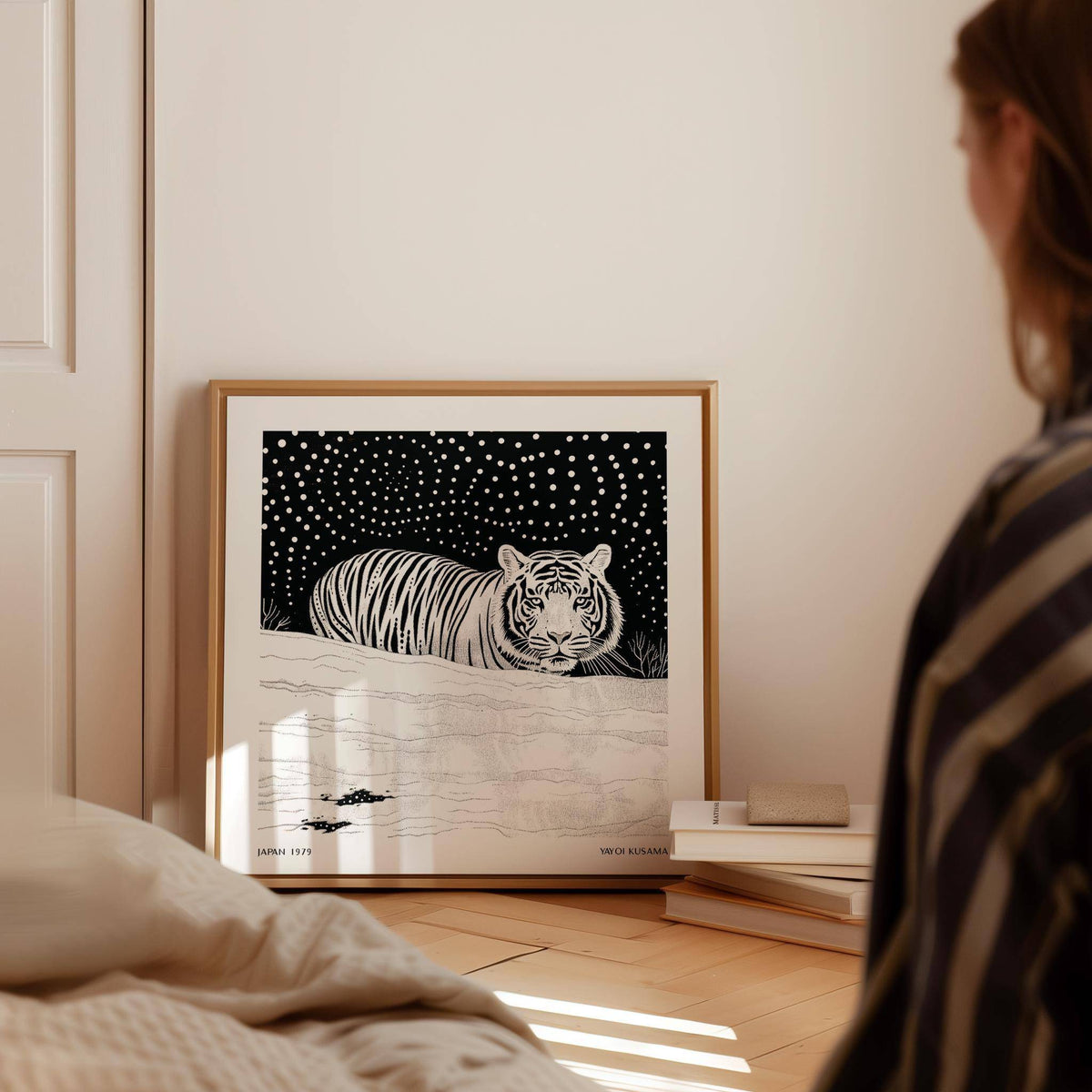 Art White Tiger print leaning on floor with stacked books in a softly lit room