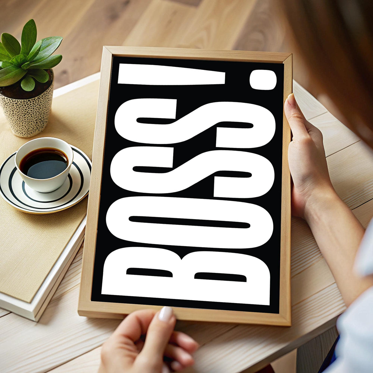 Gift for Boss framed print with bold white typography on black held in hands above a book