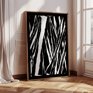 Print leaning on a wooden floor of black and white abstract lines with a curtain nearby
