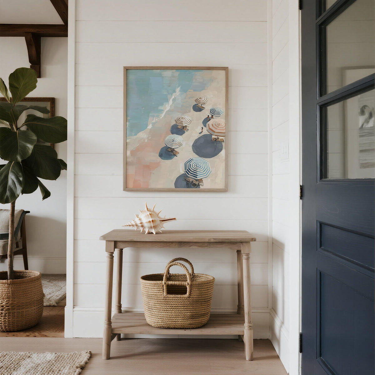 Framed Beach Umbrella Print on white wall above a console table with a sea shell and wicker basket