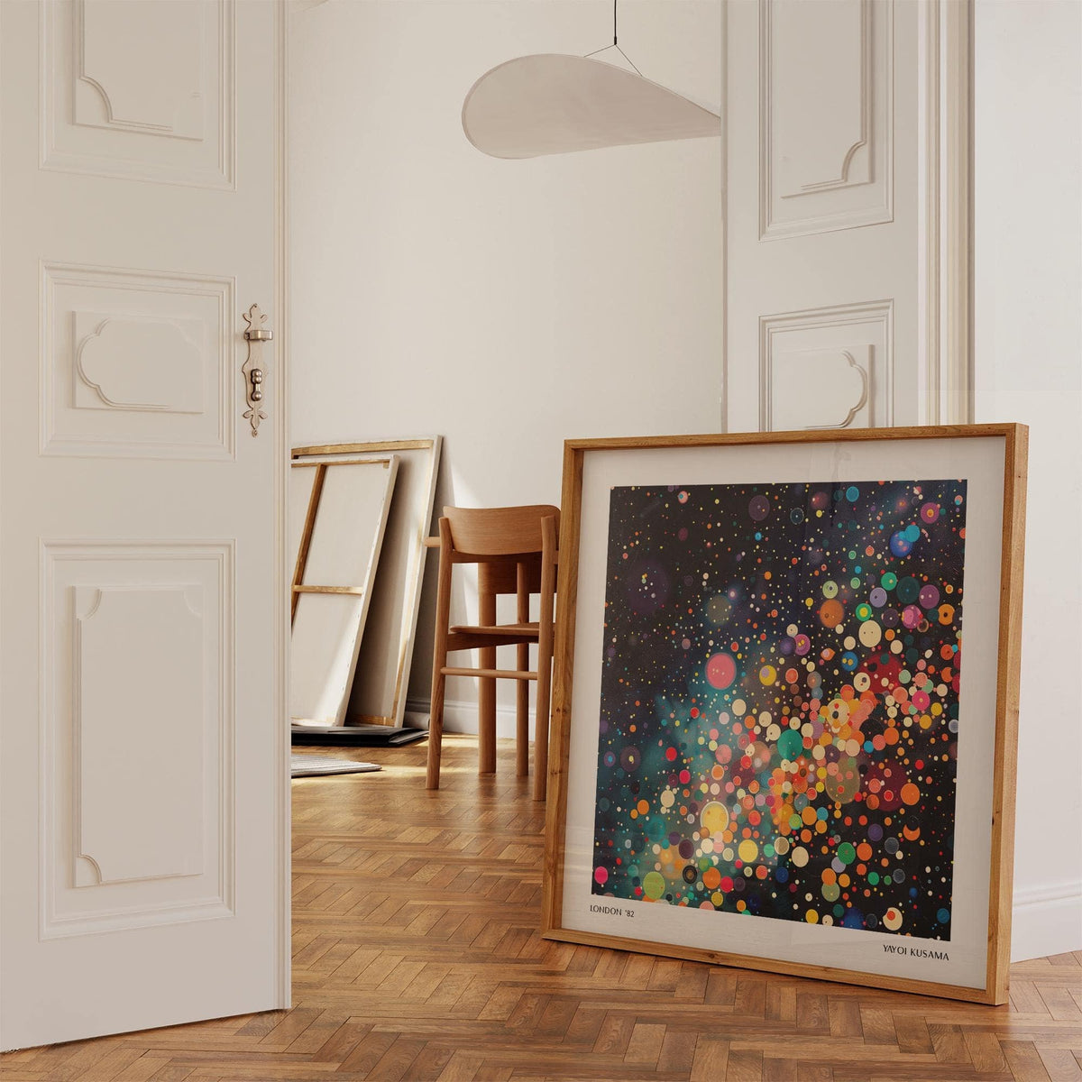 Print leaning on a shelf with Galaxy Posters colourful circles galaxy and brown frame in a room with parquet floor and wooden chair