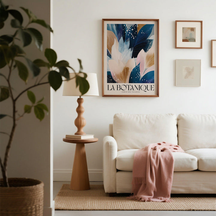 La Botanique print with blue and beige floral leaves above a beige sofa with a pink throw
