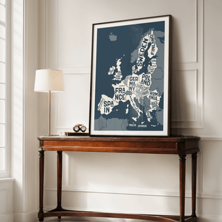Print leaning on a shelf of Europe Map Print in typographic style with dark blue and cream colours near a lamp