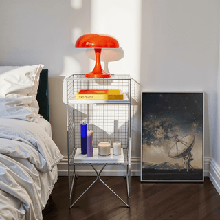 Print leaning on floor with satellite dish illustration and a red lamp on a side table