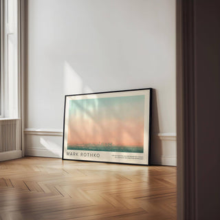 Skyline wall pictures of a city skyline at sunset with soft peach and teal hues leaning on a wooden floor