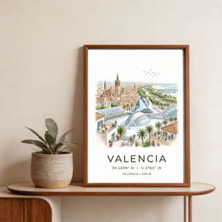 Framed print of Valencia city view illustration with watercolour tones on a wooden shelf beside a potted plant