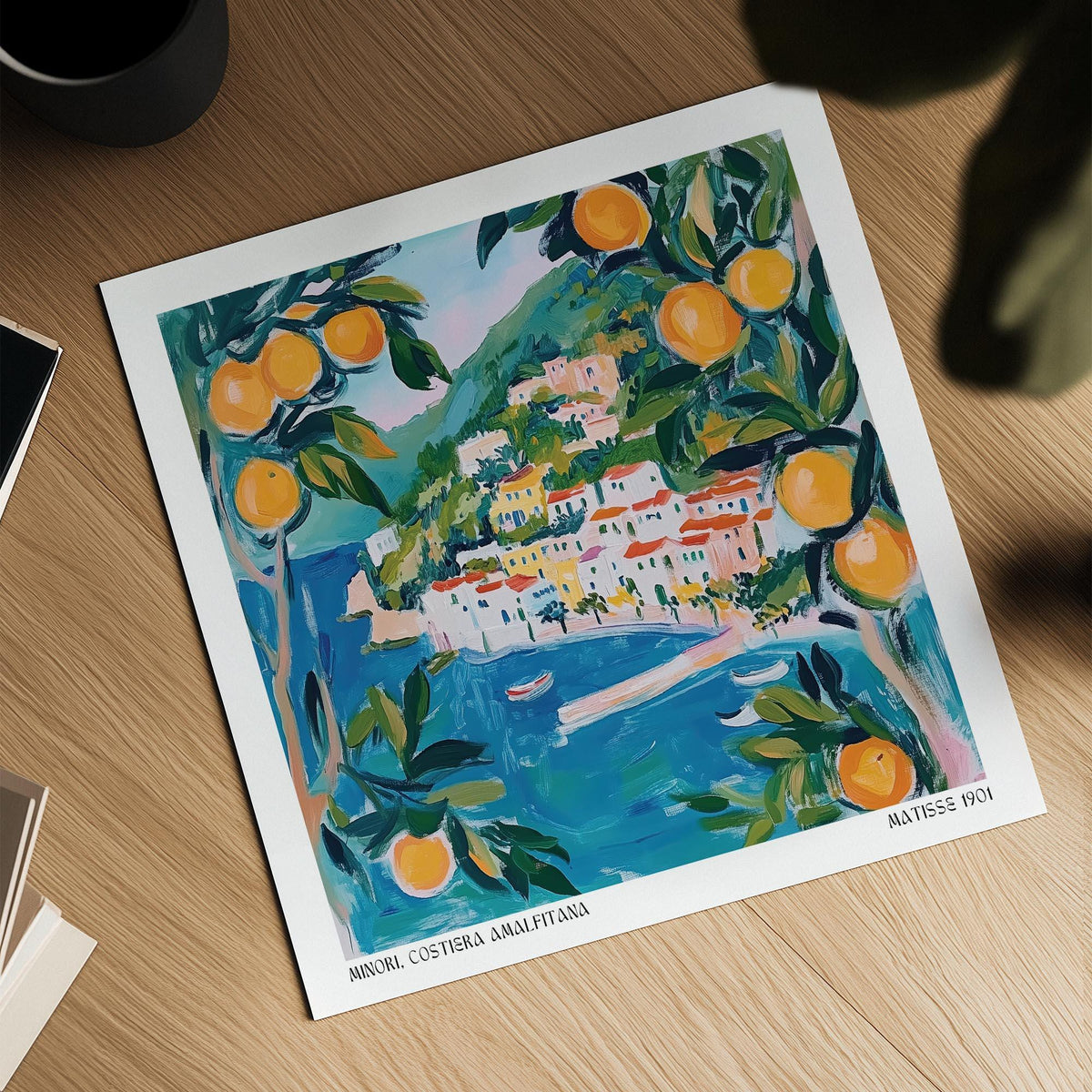 Amalfi wall art print on a wooden surface with natural light and a cup nearby