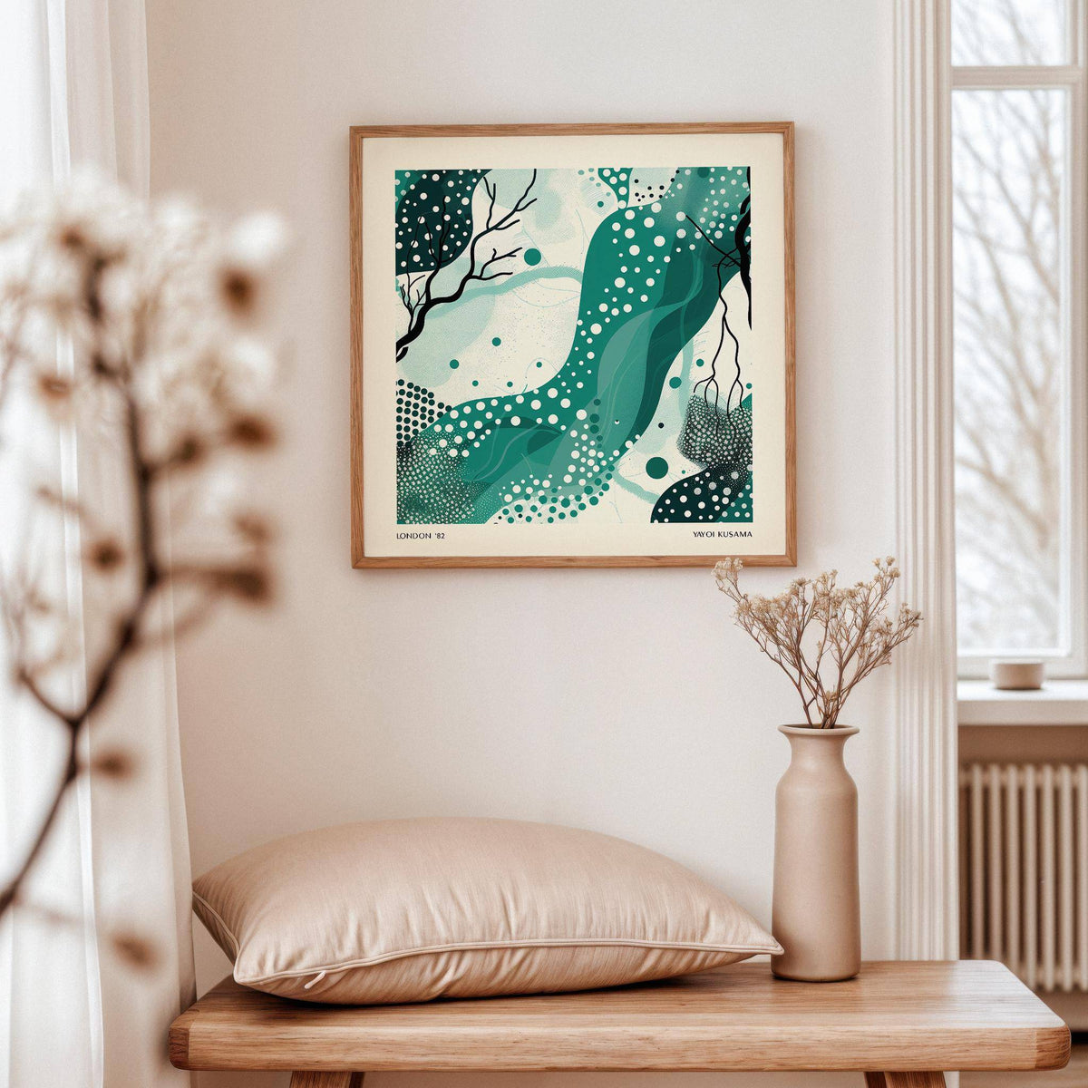 Nature wall art with abstract green shapes and white dots above a beige cushion on a wooden table