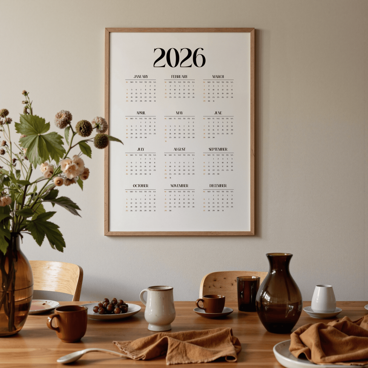 Minimalist wall calendar in a dining room above a wooden table with brown and white crockery and amber glass vase